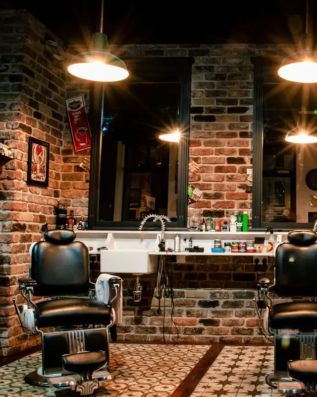 Barbearia com cadeiras de couro, parede de tijolos e luz quente