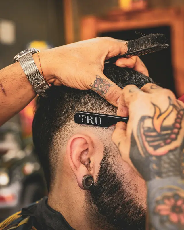 Barbeiro tatuado acertando o pezinho com a navalha