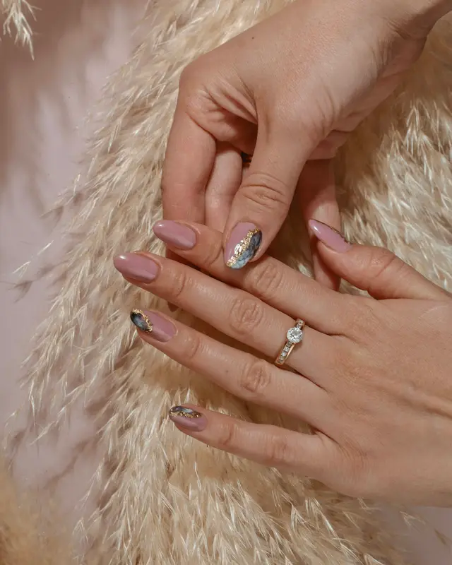 Mãos com unhas nude e detalhe metalizado