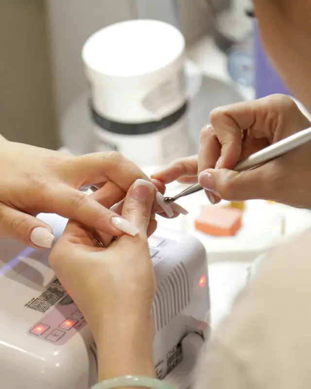 Manicure fazendo as unhas de uma cliente na mesa de atendimento