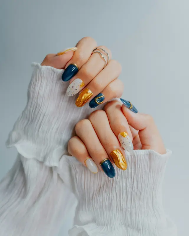 Unhas decoradas em azul, dourado e branco