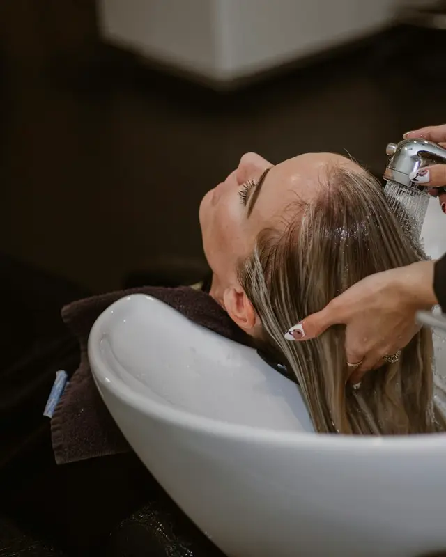 Cliente lavando o cabelo no lavatório do salão